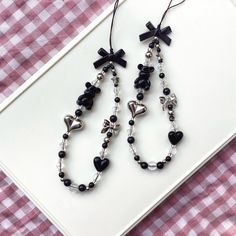 two black and white heart shaped beads on a pink checkered table cloth next to a pair of earrings