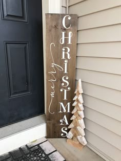 a wooden sign that says christmas on it next to a door with a small tree