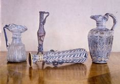 three glass vases sitting on top of a wooden table next to an empty bottle