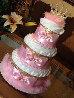 a three tiered cake with pink and white frosting, gold trimmings and a crown on top