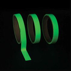 three rolls of neon green tape in the dark