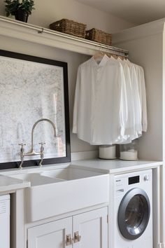 a washer and dryer in a laundry room next to a sink with clothes hanging on the rack