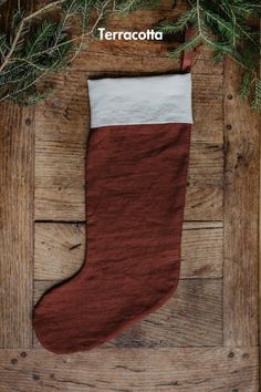 a christmas stocking hanging from a tree branch on top of a wooden floor with the words terracotta written above it