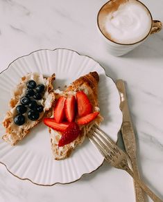 there is a piece of cake with fruit on it and a cup of coffee next to it