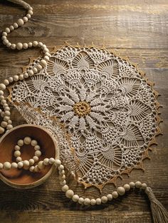 a white doily with beads and a wooden bowl next to it on a table