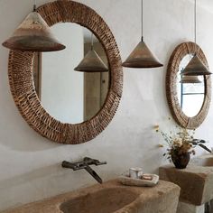 a bathroom with two sinks and mirrors hanging from the wall next to it's lights