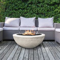 a fire pit sitting on top of a wooden floor next to couches and pillows