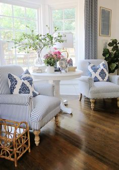 a living room with two chairs and a table in the corner, one chair has blue and white striped upholster