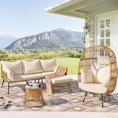 an outdoor living area with wicker furniture and mountains in the background