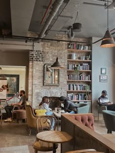 people are sitting at tables and chairs in an open room with bookshelves on the wall