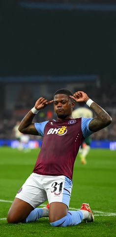 a soccer player sitting on the ground with his hands behind his head and one hand over his face