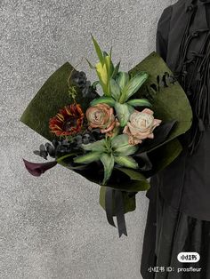 a woman holding a bouquet of flowers in her hand and wearing a black dress with long sleeves