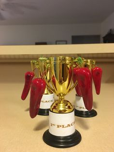 four trophies with red chili peppers on them sitting on a counter top in front of a mirror