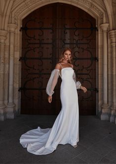 a woman in a white dress is posing for the camera with her arms spread out