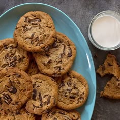 chocolate chip cookies on a blue plate next to a glass of milk