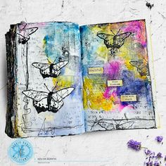 an open book with butterflies on it next to some lavenders and purple flowers in the background