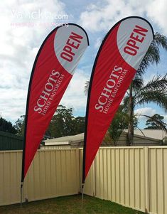 two red and white flags with the word open on them in front of a fence