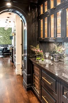 a kitchen with dark wood cabinets and marble counter tops, along with an arched doorway leading to the dining room