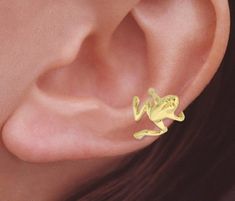 This gold Ear Cuff design comes in 2 variants: 1. 18k gold plated over Sterling Silver 2. 10k yellow gold   Our Gold Frog Ear Cuff climbs up the outer curve of your ear.  No piercing required.  Have fun wearing this playful jewelry! -*Ear Cuffs*- Ear Cuff earrings fit comfortably around the edge of your ear. They come in a variety of designs sure to catch attention and make you stand out. You can buy our cuffs as singlets or as a pair.  Ask if you have any questions. -*How It's Made*- These works are created through a multi-step process. We design, carve and modify waxes using the hands of our brilliant sculptors. The pieces are molded and cast with a personal touch. Every step of the way great care is taken to create only the best for you.  -*DIMENSIONS*- APPRX. LENGTH IN INCHES-1/2 APPRX Keroppi Cuff Earrings, Adjustable Gold Ear Climbers For Gift, Trendy Yellow Gold Ear Cuff As Gift, Trendy Yellow Gold Ear Cuff For Gift, Trendy Clip-on Ear Cuff As Gift, Trendy Clip-on Ear Cuff For Gift, Yellow Gold Clip-on Ear Cuff For Gift, Yellow Gold Clip-on Ear Cuff As Gift, Egirl Earrings