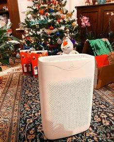 a white air purifier sitting in front of a christmas tree