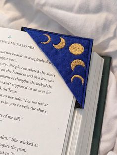 an open book with a blue and gold triangle on it's cover next to a white sheet