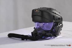 a helmet with a microphone attached to it on top of a white sheeted surface