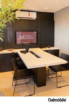 a table with chairs and a laptop on it in front of a flat screen tv