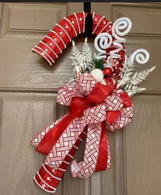 a red and white christmas wreath hanging on a door