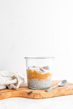 a glass jar filled with food sitting on top of a wooden cutting board next to a white wall