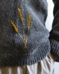 a close up of a person wearing a gray sweater with yellow flowers on the side