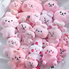 a pile of pink teddy bears sitting on top of a white table covered in stuffed animals