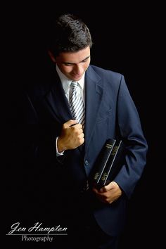 a man in a suit and tie is holding two books while looking down at his jacket