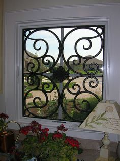 a window that has some flowers in it and a lamp on the table next to it