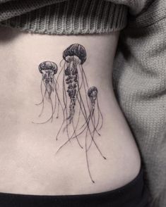 a woman's stomach with three jellyfish tattoos on her side ribcage