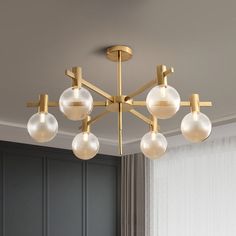 a chandelier hanging from the ceiling in a room with gray walls and curtains