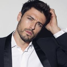 a man in a tuxedo is posing for a photo with his hand on his head