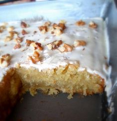 a cake with white frosting and walnuts on top is cut into pieces to show the inside