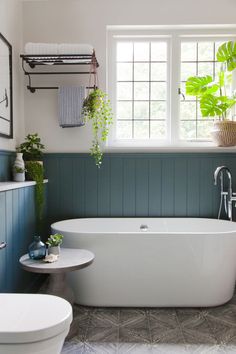 a white bath tub sitting under a window next to a toilet