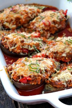 stuffed eggplant in a white casserole dish with sauce and herbs on top