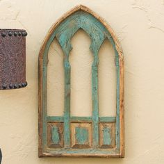 an old stained glass window on the side of a wall next to a light fixture