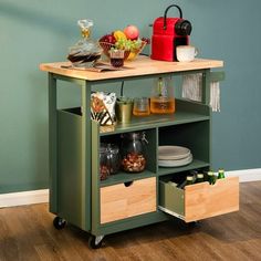 a kitchen cart with food and drinks on it in front of a green painted wall