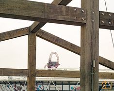 a ferris wheel is seen through the wooden structure