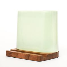 a wooden stand with a light green glass block on it's top and wood base