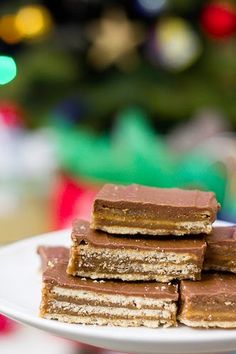 a white plate topped with pieces of cake next to a christmas tree in the background