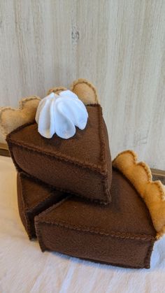 three pieces of chocolate pie with whipped cream on top, sitting on a white surface