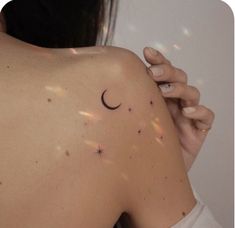 the back of a woman's shoulder with stars and a crescent tattoo on it