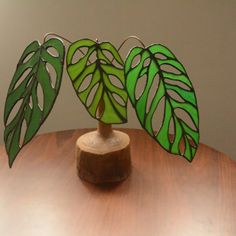 three green leaves are on top of a wooden stand that is sitting on a table