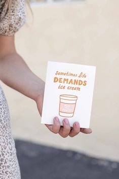 a woman holding a card that says sometimes life demands ice cream