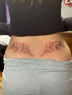 a woman's lower back tattoo with flowers on her left side ribcage