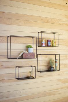 three metal shelves with plants on them against a wooden wall